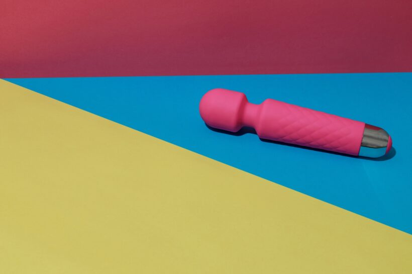 Pink dildo vibrator for satisfaction on colored background with shadows. Sex toy for adult