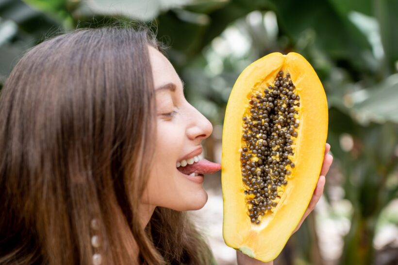 Portrait of a woman licking papaya fruit