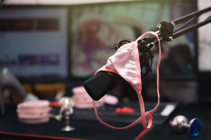 Women pink panties on a studio microphone with a metal anal plugs on the streamer table. Online sex