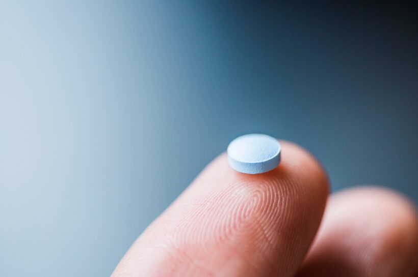 Close-up of hand holding blue pill