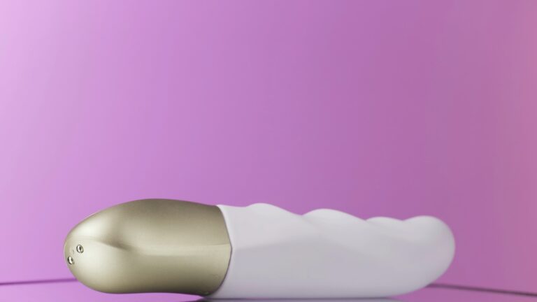 A luxus vibrátor fogalma Close up of white vibrator with a golden handle rotating. Action. New sex toy spinning isolated on a