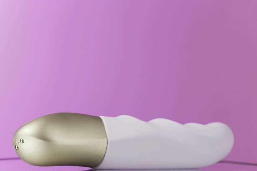 Close up of white vibrator with a golden handle rotating. Action. New sex toy spinning isolated on a