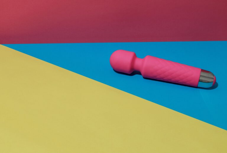 Hogyan teheted izgalmasabbá a vibrátorozást? Pink dildo vibrator for satisfaction on colored background with shadows. Sex toy for adult