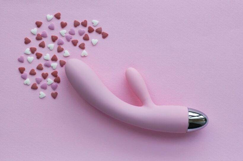 Pink vibrator toy for adults lies on a pink background